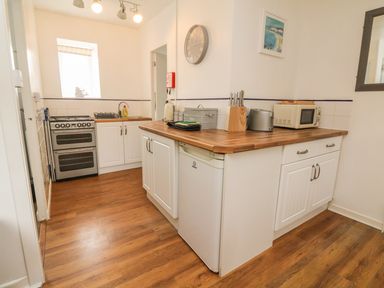 A kitchen with a stove sink fridge microwave and knives at Wren Cottage Ilfracombe