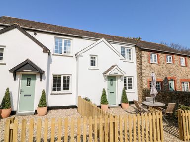A row of cottages with green doors and a wooden fence in front at Martin Cottage in Ilfracombe