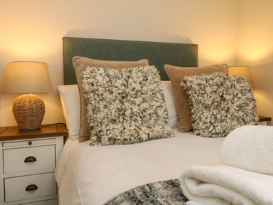A bed with decorative pillows bedside tables with lamps and folded towels on the bed at Martin Cottage in Ilfracombe