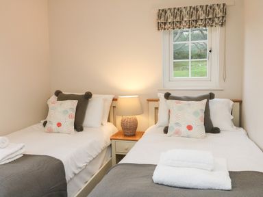 A bedroom with two single beds and a lamp on a bedside table at Kingfisher Cottage in Ilfracombe