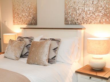 A bed with pillows and two bedside tables with lamps in a bedroom at Kingfisher Cottage in Ilfracombe