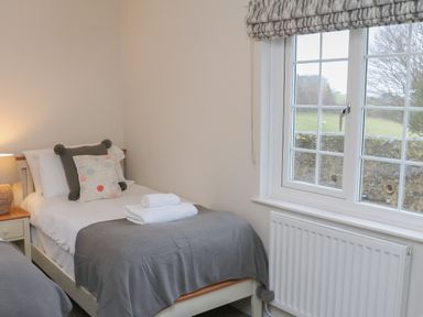 A bedroom with a single bed next to a window and a bedside table with lamp at Kingfisher Cottage in Ilfracombe