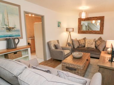 A living room with sofas armchair coffee table and large framed mirror at Kingfisher Cottage in Ilfracombe