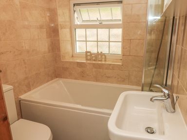 A bathroom with a bathtub sink toilet and window at Partridge Cottage in Ilfracombe