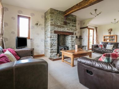 A living room with leather sofas a wooden coffee table and a stone fireplace at Blaen Henllan in Builth Wells