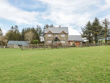 A stone house with a slate roof surrounded by grass and trees at Blaen Henllan in Builth Wells