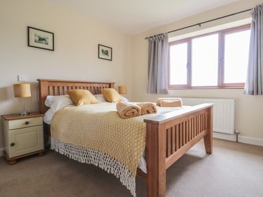 A bedroom with a wooden bed and two bedside tables with lamps at Blaen Henllan in Builth Wells