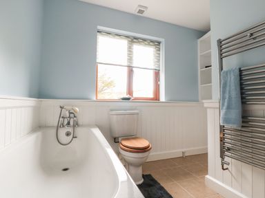 A bathroom with a bathtub a toilet a window and a towel rack at Blaen Henllan in Builth Wells