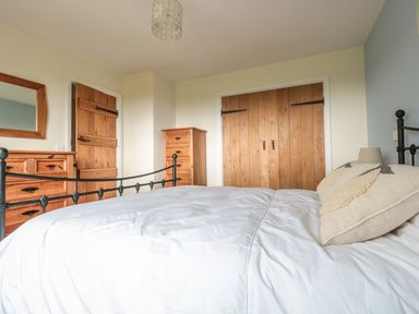 A bedroom with a bed a wooden dresser a wooden wardrobe and wooden doors at Blaen Henllan in Builth Wells