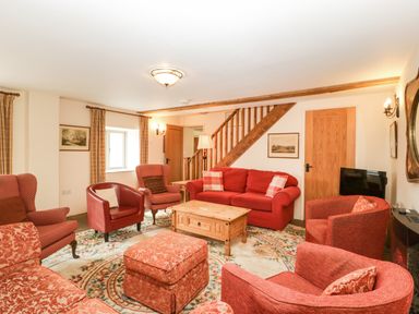 A living room with red sofas armchairs and a wooden coffee table at Timber Barn in Eardisland