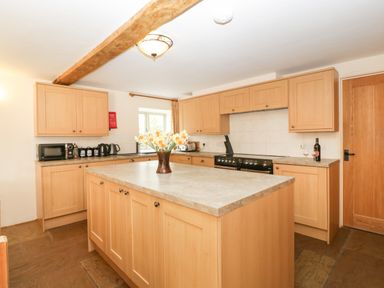 A kitchen with wooden cabinets an island countertop and appliances at Timber Barn in Eardisland