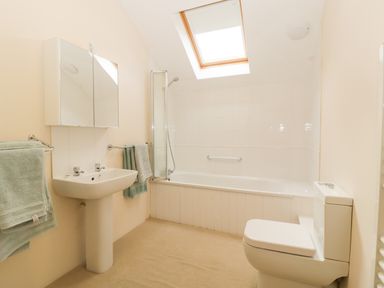 A bathroom with a toilet sink bathtub towel racks and skylight at Timber Barn in Eardisland
