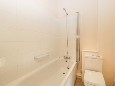A bathroom with a bathtub and showerhead next to a toilet at Timber Barn in Eardisland