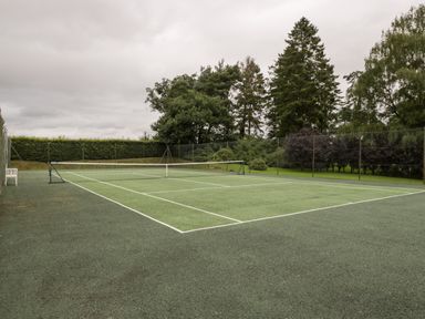 An outdoor tennis court surrounded by trees and fencing at Timber Barn in Eardisland
