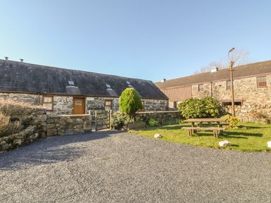 A gravel driveway and a picnic bench in front of stone buildings at Beudy Bach in Y Felinheli