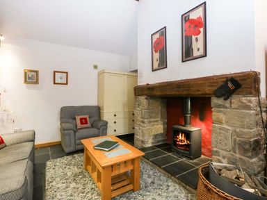 A living room with a fireplace and seating area at Beudy Mawr Y Felinheli