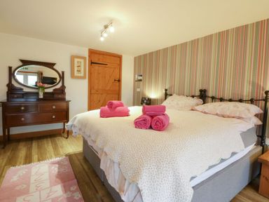 A bedroom with a bed and dresser at Beudy Mawr Y Felinheli