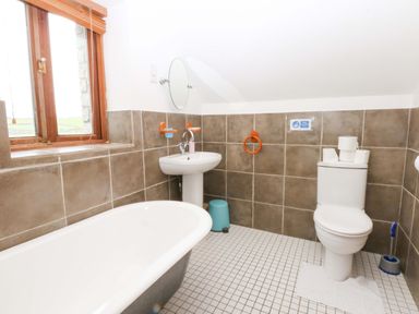 A bathroom with a bathtub, toilet and sink at Beudy Mawr Y Felinheli