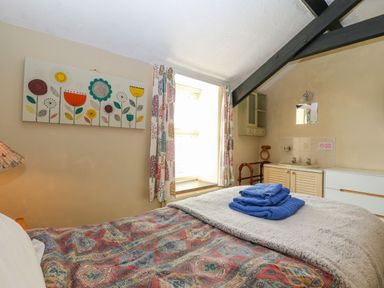 A bedroom with a bed a stack of blue towels a window and a sink cabinet at Hendre in Y Felinheli