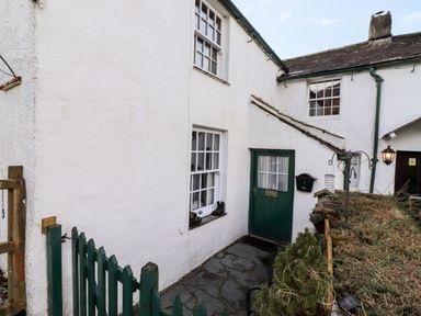 An outdoor entrance area with a green door and windows on a white building at Castle Lodge in Borrowdale