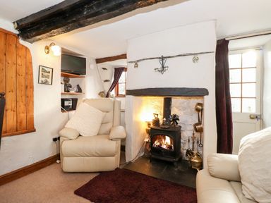 A sitting area with armchairs and a wood stove fireplace at Castle Lodge in Borrowdale
