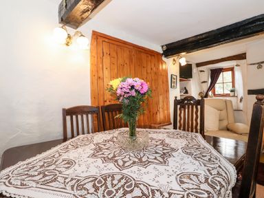 A dining room with a table covered by a lace tablecloth and a vase with flowers at Castle Lodge in Borrowdale