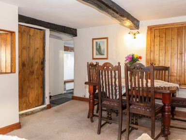A dining room with wooden table and chairs and a flower vase at Castle Lodge in Borrowdale