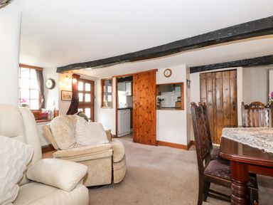 A living room with armchairs wooden dining table and chairs and a kitchen door at Castle Lodge in Borrowdale
