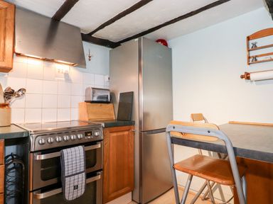 A kitchen with a stainless steel oven stove a refrigerator wooden cabinets a table with chairs and a wall-mounted paper towel holder at Castle Lodge Borrowdale