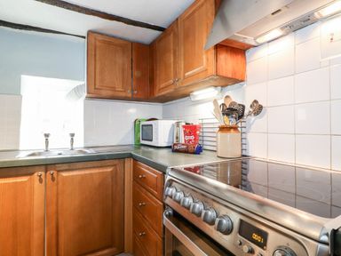 A kitchen with wooden cabinets a stainless steel stove a microwave and a sink at Castle Lodge in Borrowdale