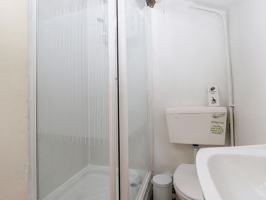 A bathroom with a shower cubicle toilet sink and disposal bag at Castle Lodge in Borrowdale
