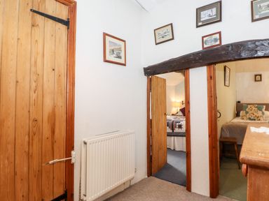 A hallway with wooden doors and framed pictures on the walls at Castle Lodge in Borrowdale