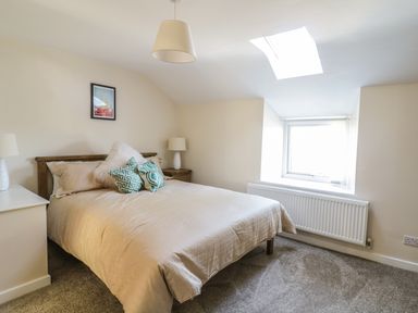 A bedroom with a double bed two bedside tables with lamps a window and a skylight at Y Cilgwyn in Trawsfynydd
