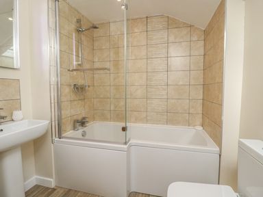 A bathroom with a bathtub shower combination pedestal sink and toilet at Y Cilgwyn in Trawsfynydd
