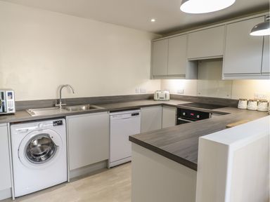 A kitchen with a washing machine microwave toaster stove and cabinets at Y Cilgwyn in Trawsfynydd