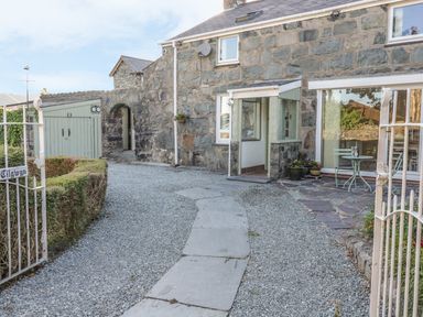 Stone house with gravel pathway and small patio table and chairs at Y Cilgwyn in Trawsfynydd