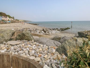 A rocky beach with houses along the shore and the sea in the background at Pottery Cottage in Begelly near Kilgetty