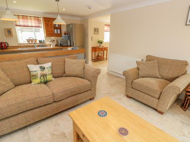 A living room with two patterned sofas and a wooden coffee table with coasters at Pottery Cottage in Begelly near Kilgetty