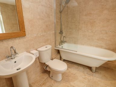 A bathroom with a pedestal sink toilet and bathtub with shower at Pottery Cottage Begelly near Kilgetty
