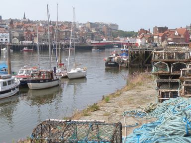 A harbor with fishing boats moored by the quay and lobster pots stacked on the dock at Flat 4 in Whitby