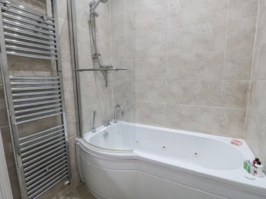 A bathroom with a bathtub with shower and a chrome towel radiator at Flat 4 in Whitby