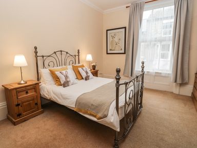 A bedroom with a metal bed frame and bedside tables with lamps at Flat 4 Whitby