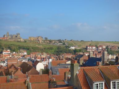 A town with red rooftops and an old abbey on a hill in the background at Flat 4 in Whitby