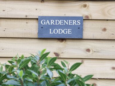 A wooden wall with a sign that reads Gardeners Lodge and some green leaves in front at Gardeners Lodge in Nantwich