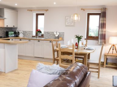 A kitchen and dining area with wooden chairs and table with dining set at Gardener's Lodge in Nantwich
