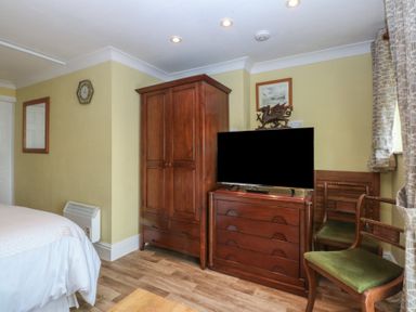 A bedroom with a wooden wardrobe and television at Maesawel Studio Llanfair