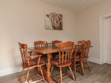 A dining room with a wooden table and chairs at The Farmhouse in Brynsiencyn near Newborough