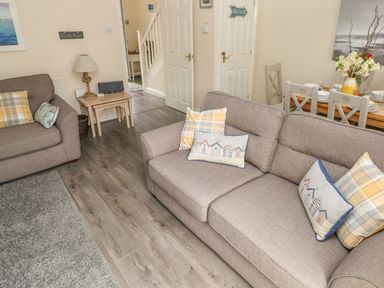 A living room with two sofas a small table with a lamp and a dining table with chairs at Sandy Bay House in Saundersfoot