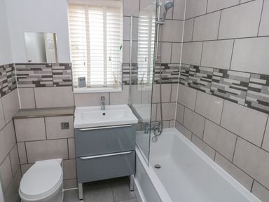 A bathroom with a toilet sink and bathtub with shower at Sandy Bay House in Saundersfoot