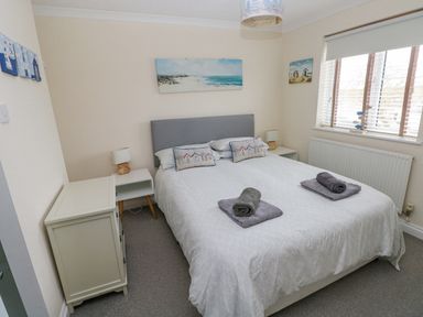 A bedroom with a double bed and bedside tables with lamps at Sandy Bay House in Saundersfoot